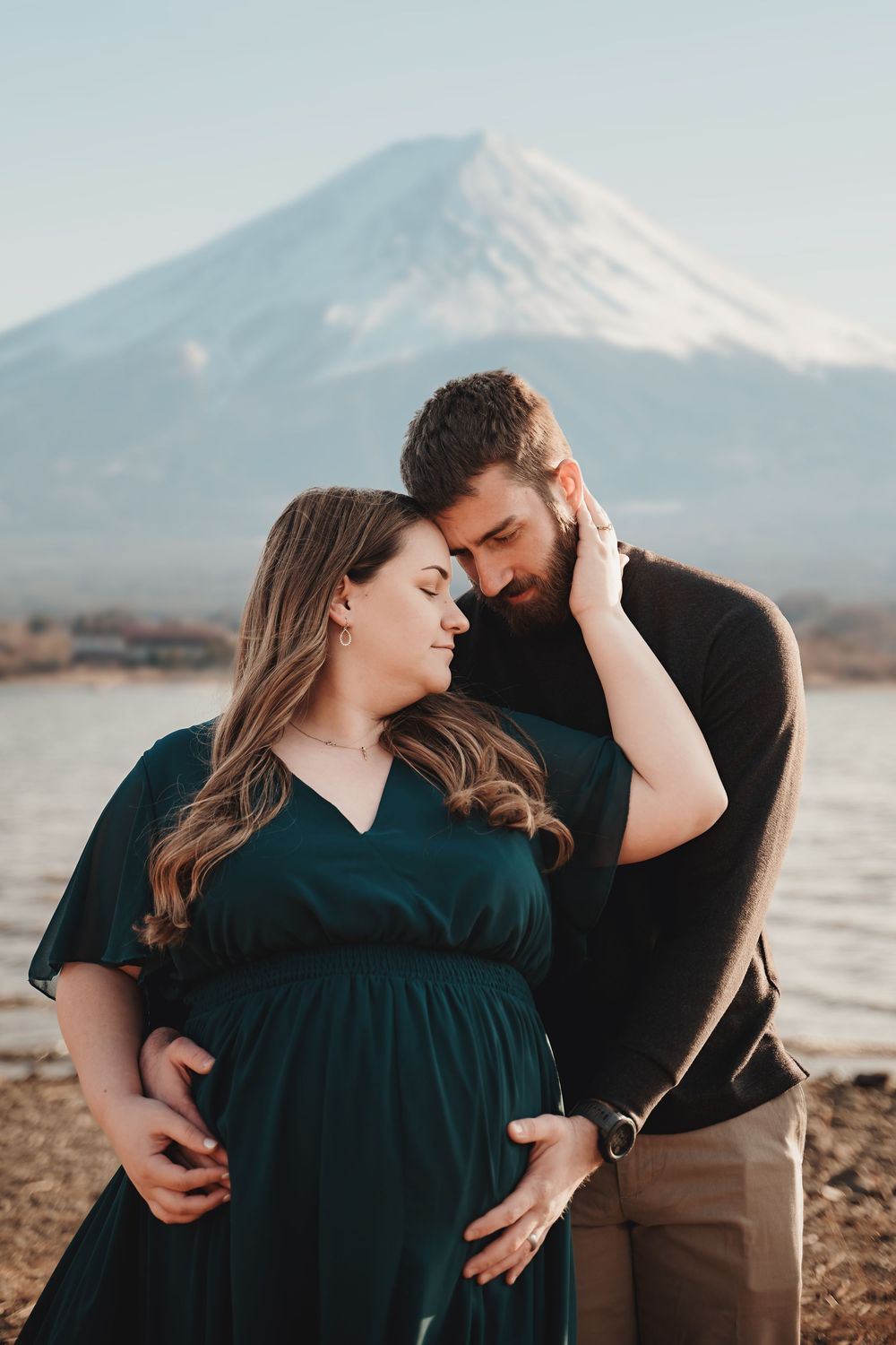 Couple shares intimate moment near Mount Fuji as they await their baby's arrival, photographed at sunset.