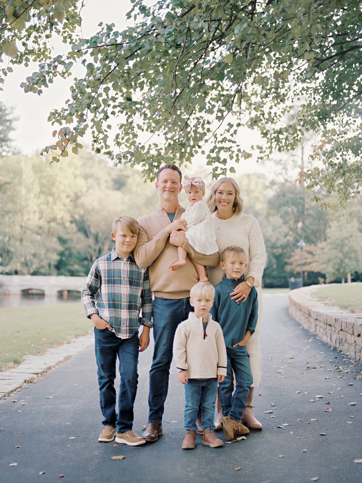 A family group stands together on a grassy slope beside a serene lake.