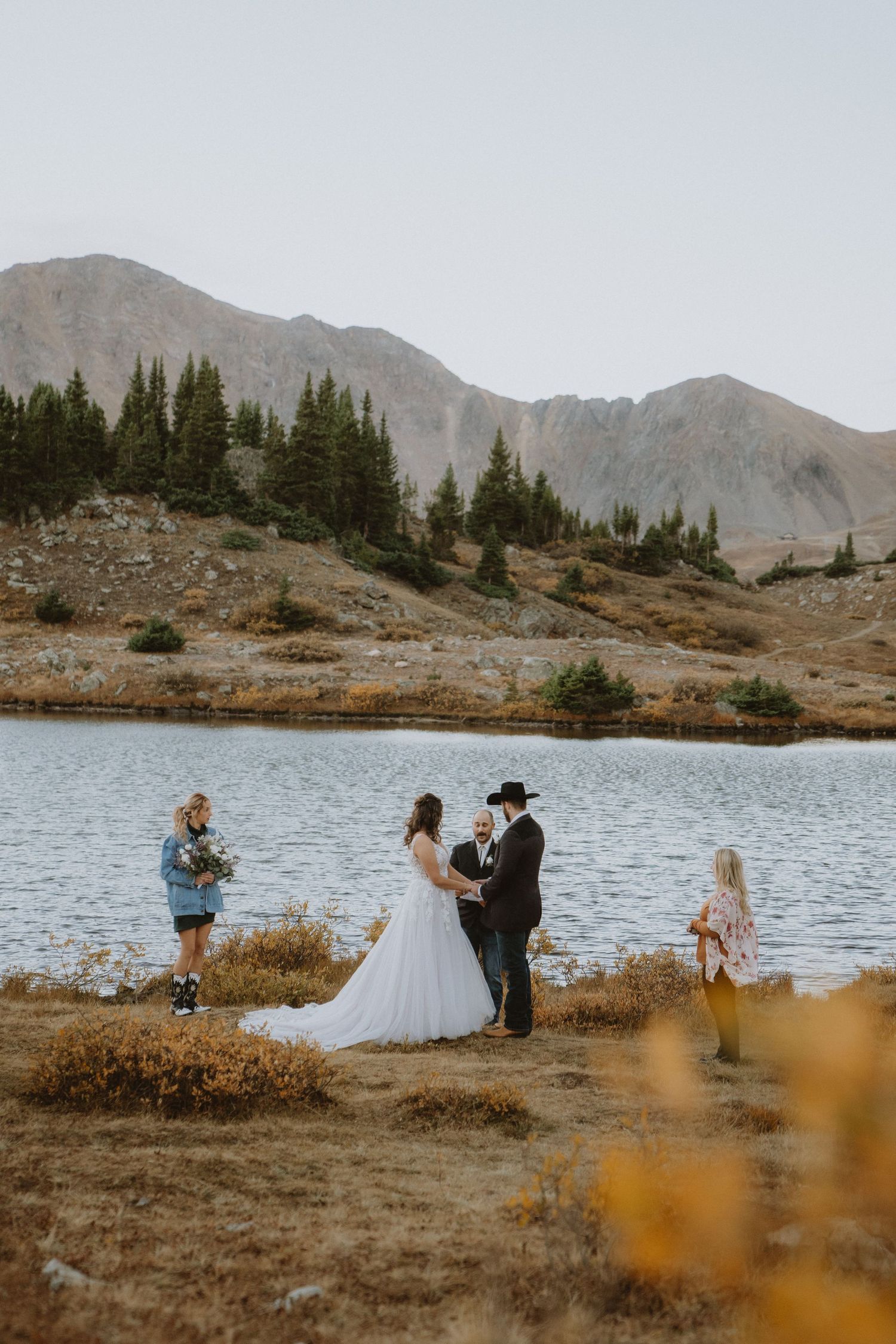 Winter wedding photo with bride in fur shawl and groom walking in snowy mountain landscape.