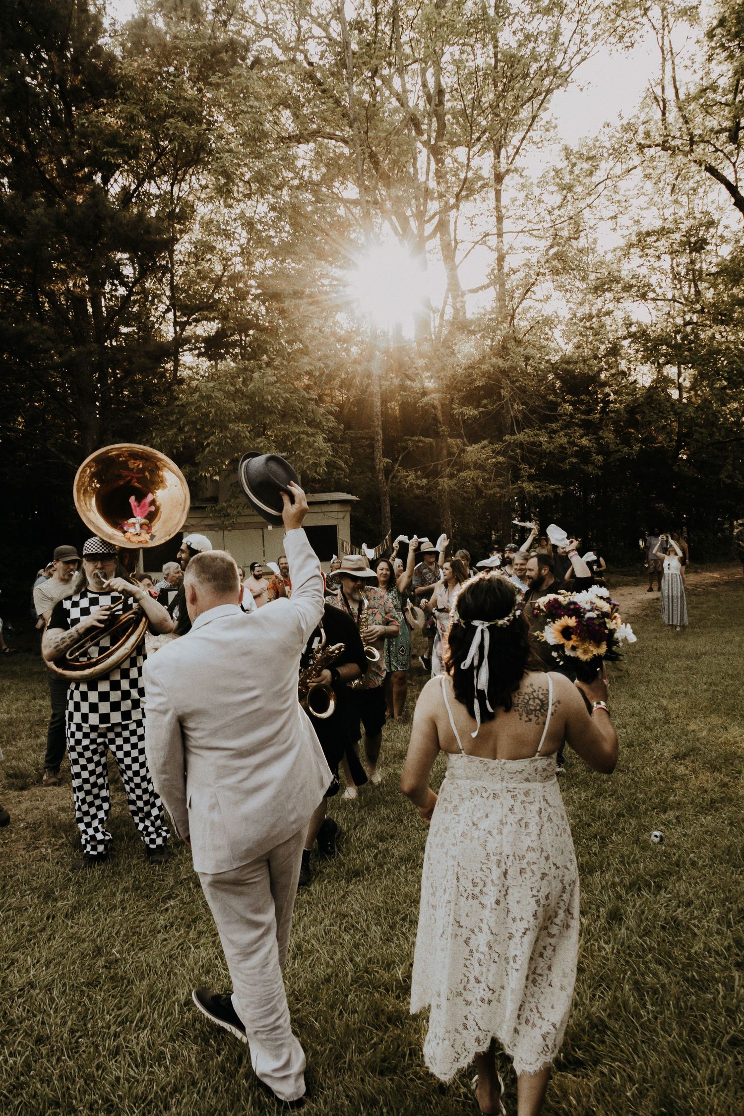 A lively outdoor wedding celebration with a brass band playing music at sunset.