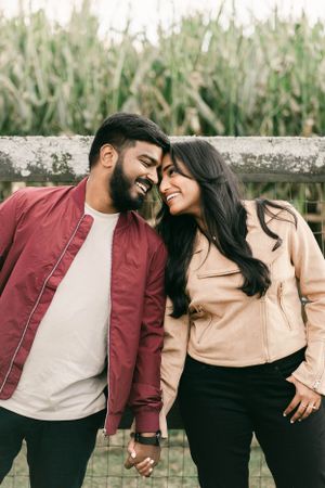 Romantic couple in casual attire sharing intimate moments outdoors against a natural backdrop.