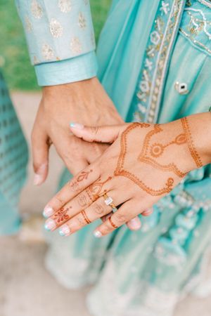 Detailed shots of intricate henna designs on hands with a diamond engagement ring.