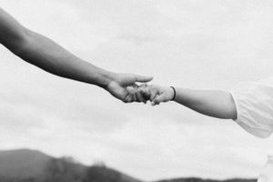Black and white close-up of hands reaching toward each other.