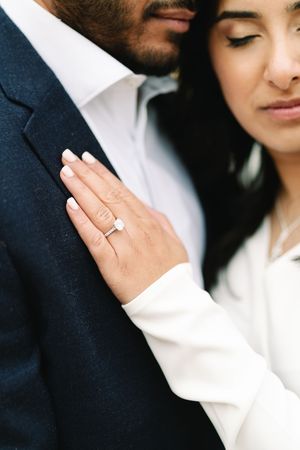 Close-up of an engaged couple, woman wearing a elegant solitaire diamond engagement ring on her finger.