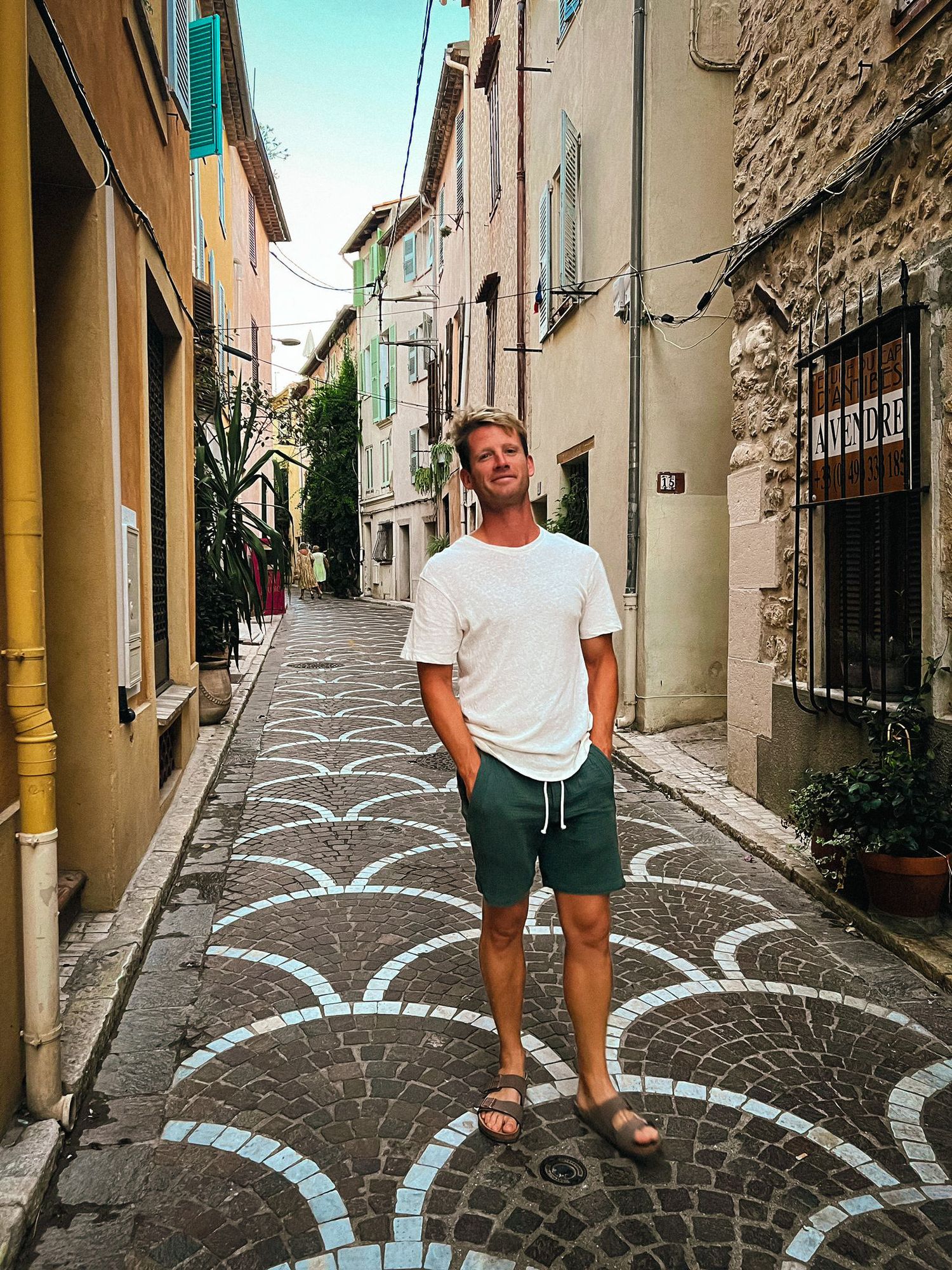 Scenic narrow cobblestone street in an Italian village with decorative white curved patterns on the ground.