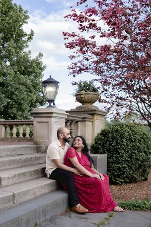 A couple sits on elegant stone steps with decorative lamp post and Japanese maple tree in a garden setting.