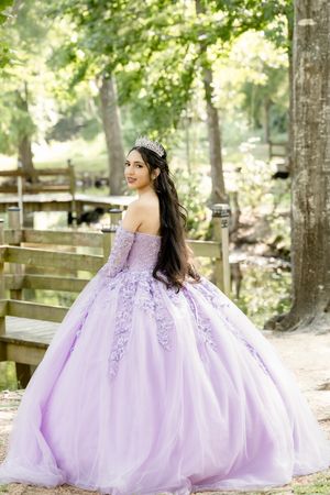 Lavender ball gown with lace appliques photographed in an outdoor woodland setting.