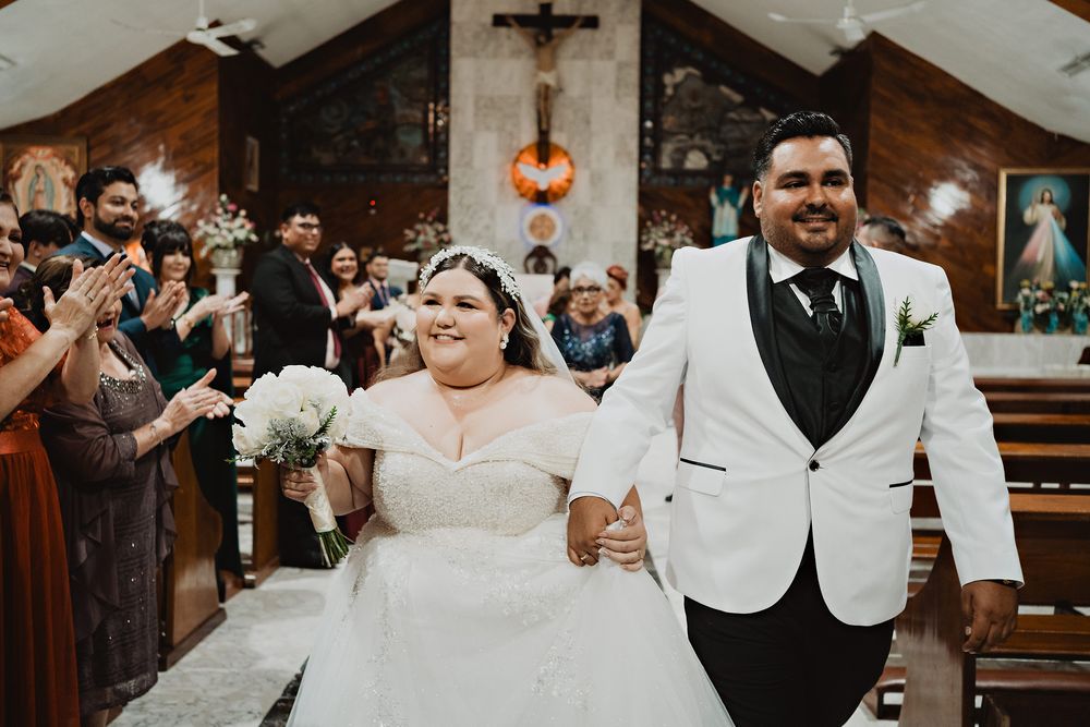Newlyweds joyfully exit church aisle while guests celebrate their marriage.