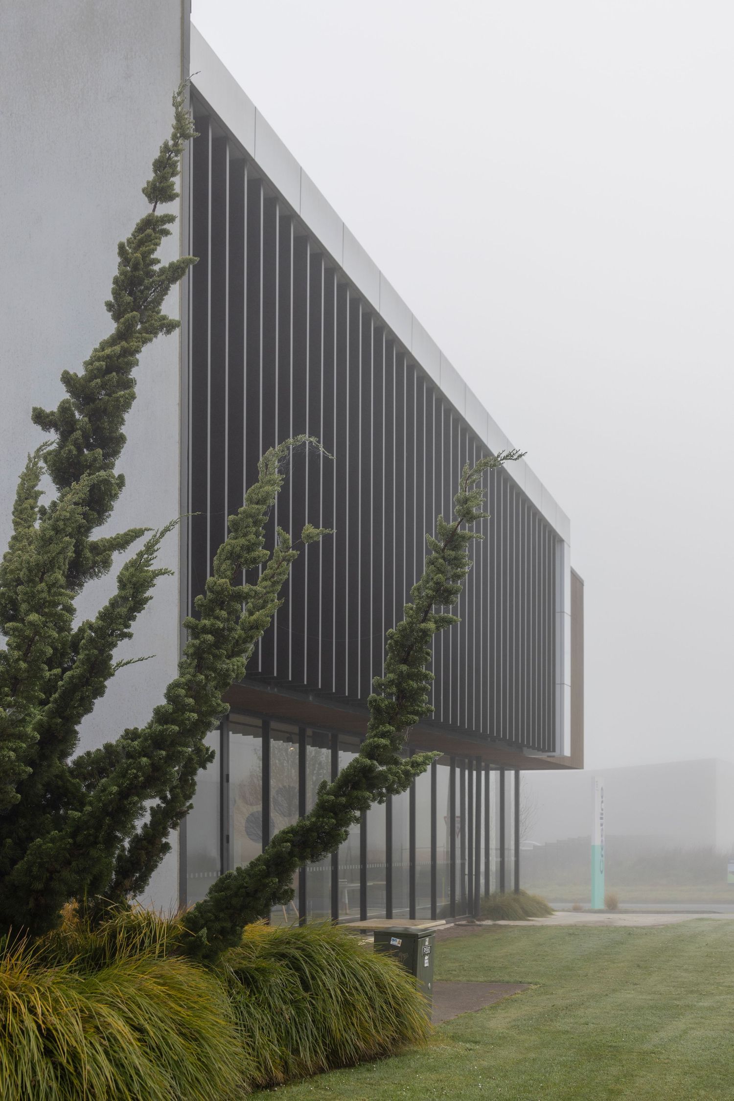 Sleek black building with sharp angles, set against a misty foggy landscape.