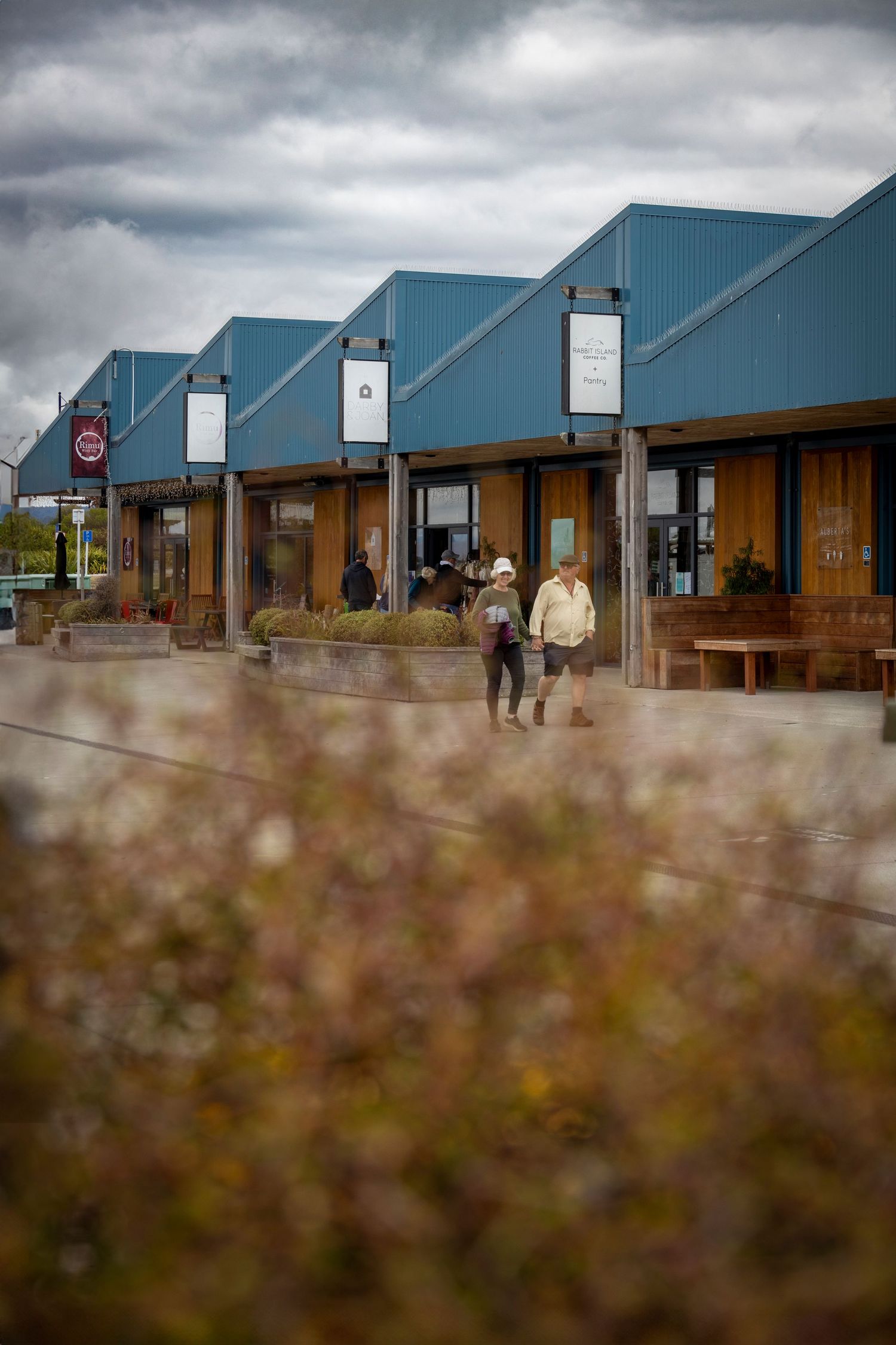 People walking past quaint shops with pitched blue roofs and timber details.