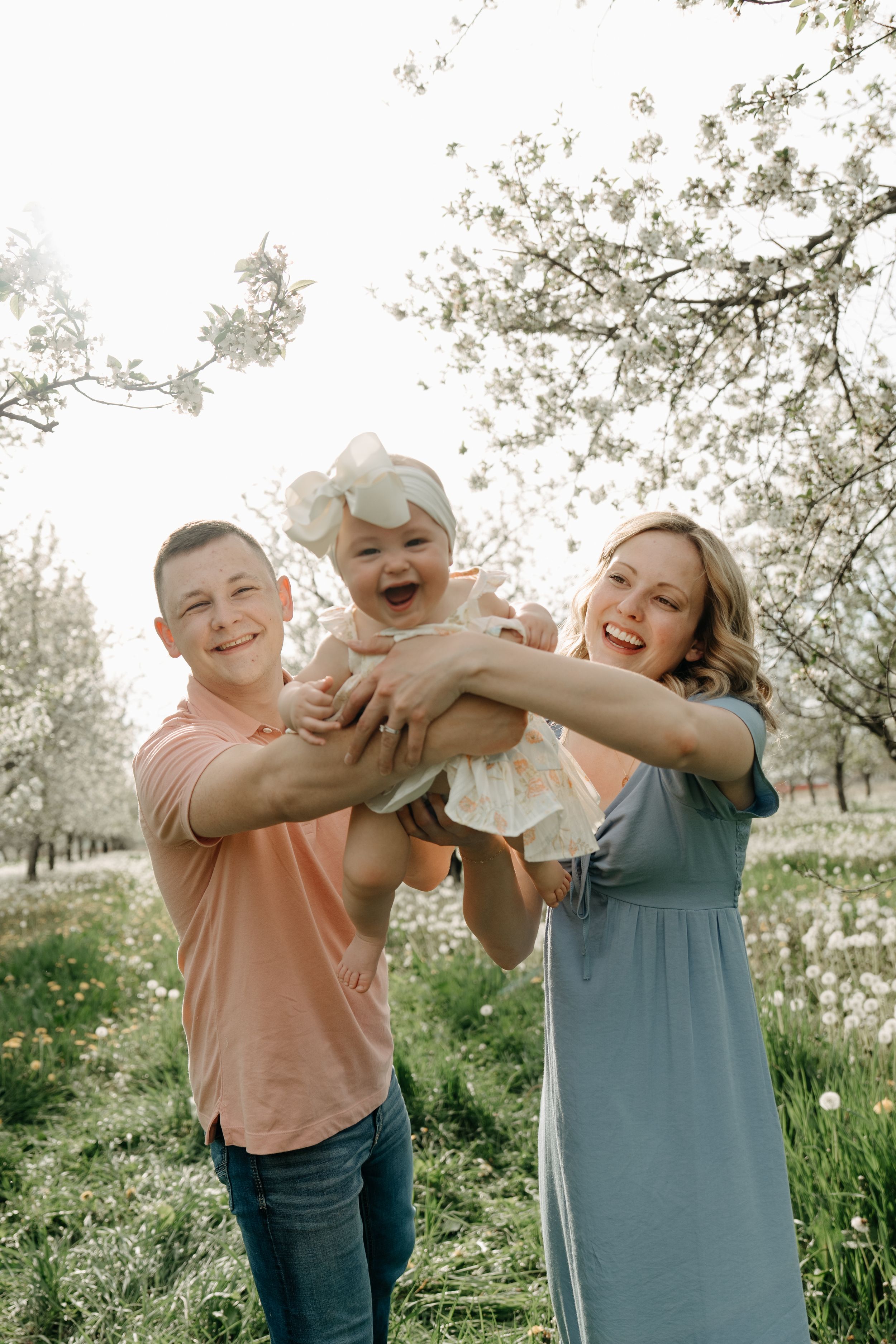 A joyful family moment outside in a spring orchard with blooming trees and wildflowers.