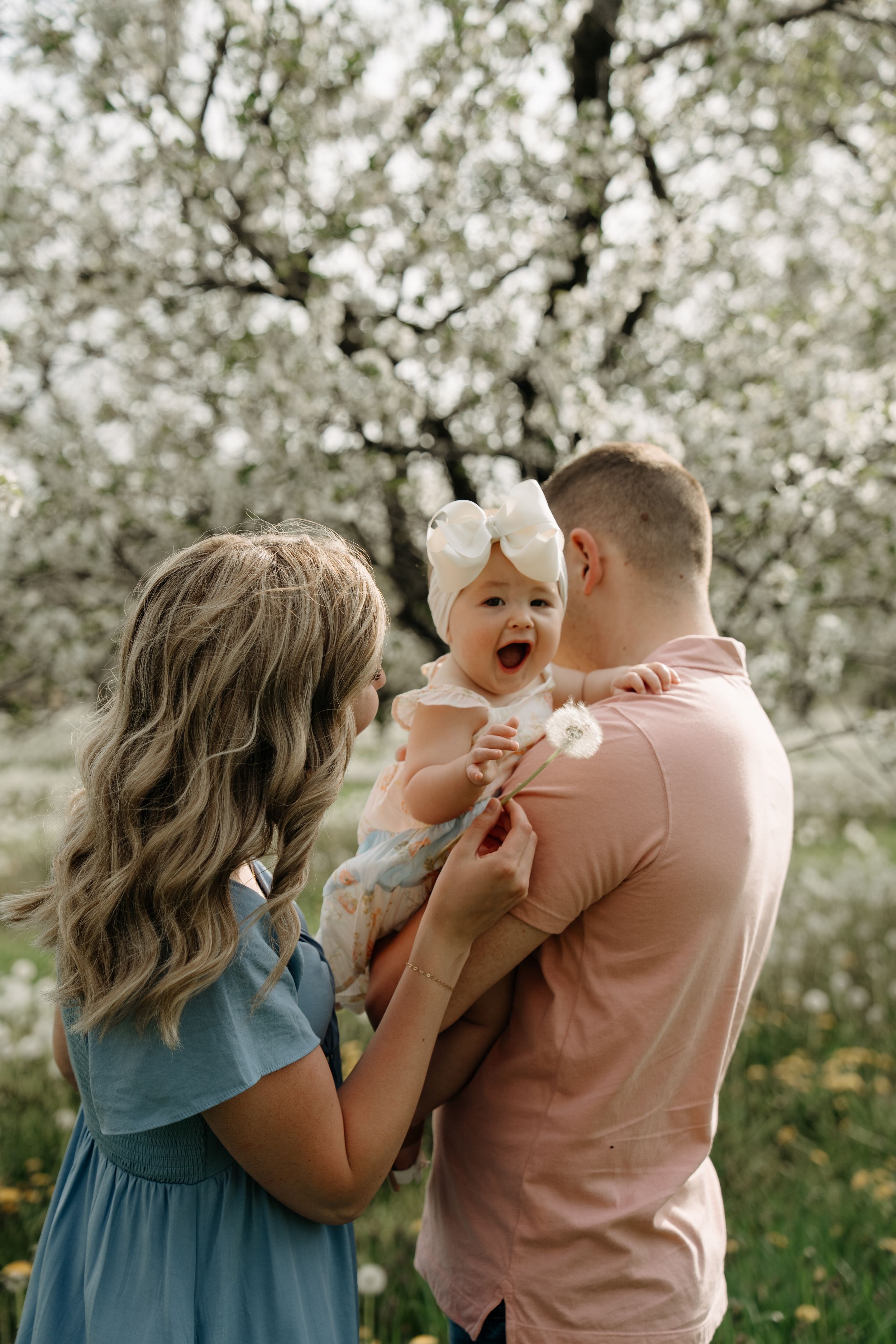 A family shares a joyful moment outdoors surrounded by blooming cherry blossoms on a spring day.