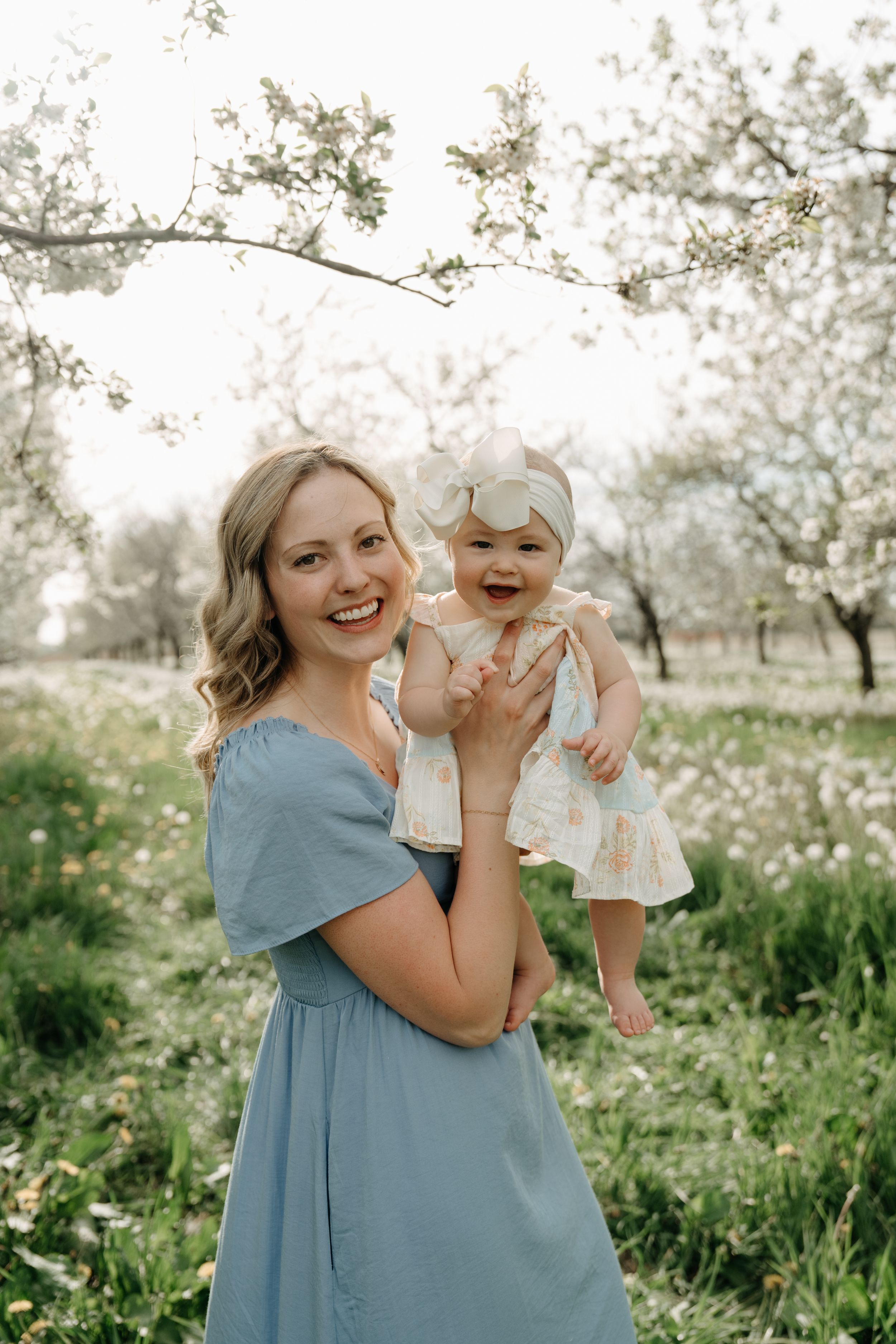 A joyful moment captured in a spring orchard with blooming trees and scattered wildflowers in soft natural light.