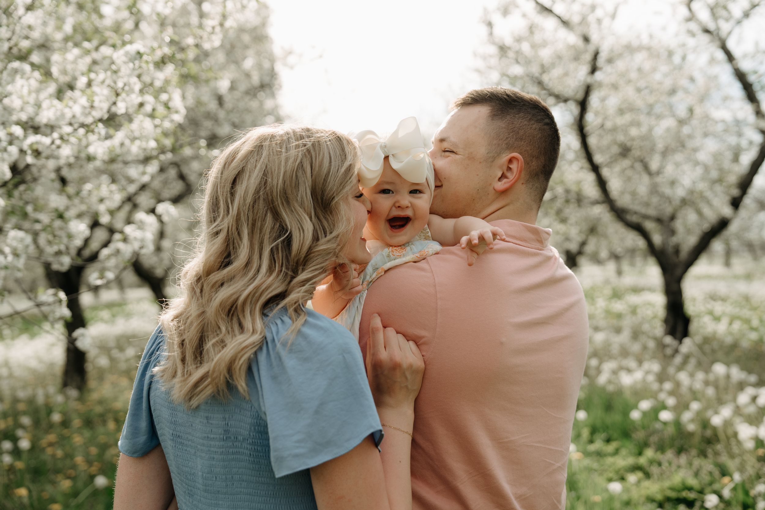 A couple shares a tender moment in a blooming cherry blossom orchard on a spring day.