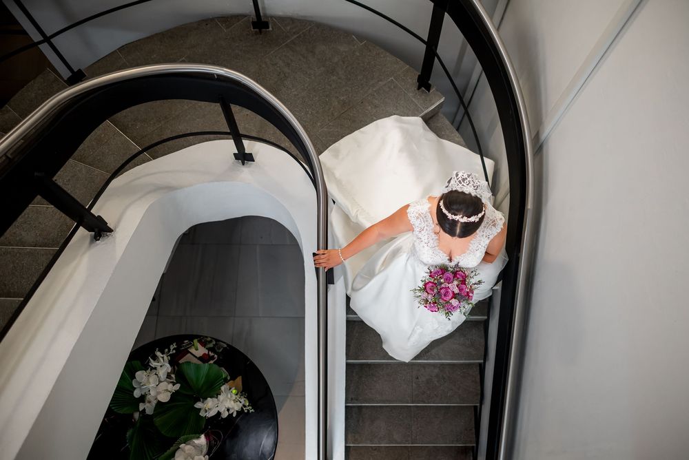 Aerial view of spiral staircase with wedding dress and bouquet displayed on banister.