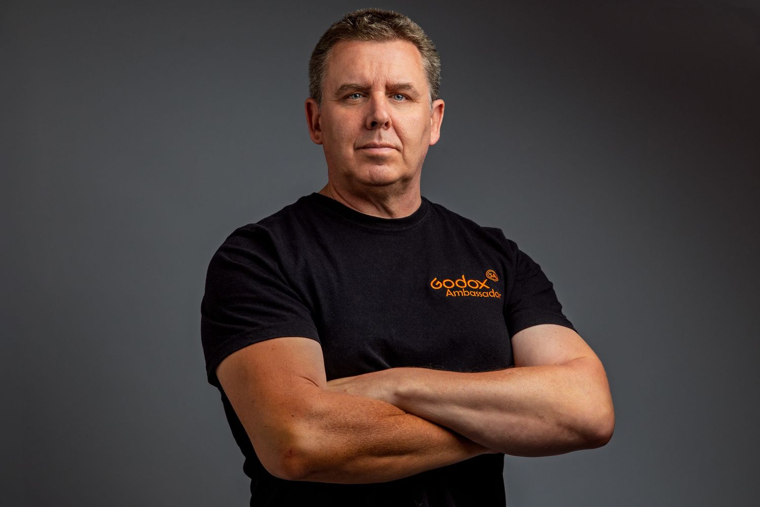 Professional headshots of person in black t-shirt against grey studio background.