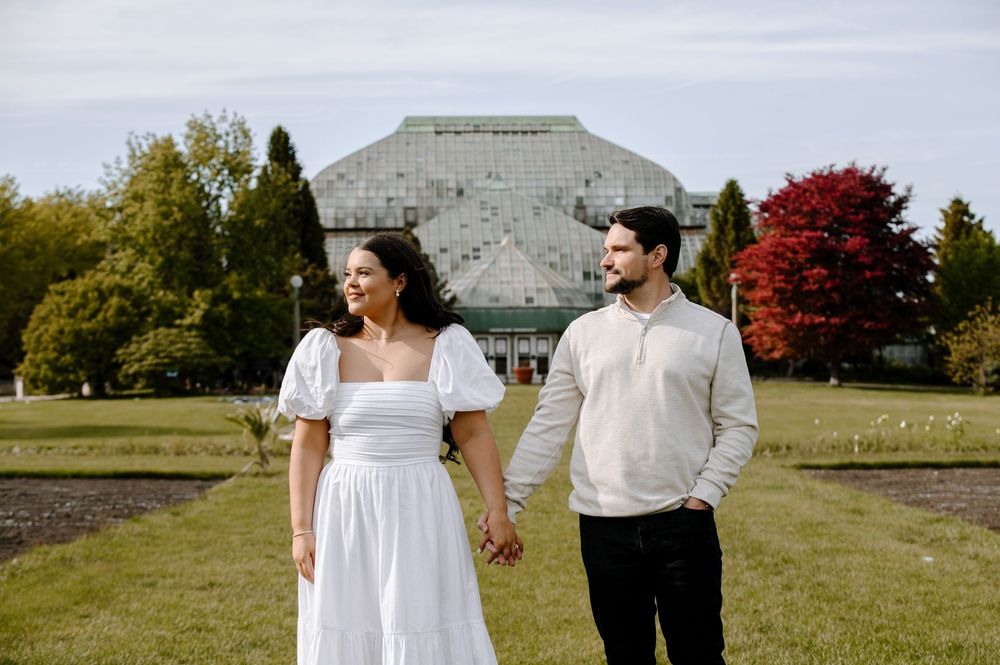 Two people embrace while standing in a scenic park setting on a bright autumn day.