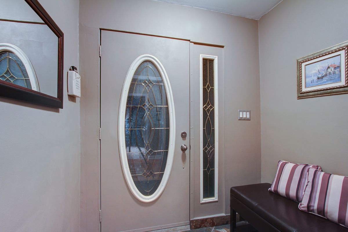 Modern entryway with an elegant oval glass door and decorative sidelights, complemented by a bench.