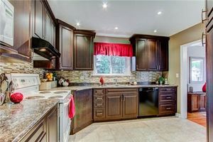 Modern kitchen featuring dark wood cabinetry and red valance window treatment.