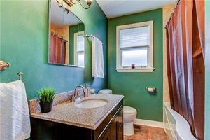 Stylish bathroom featuring green walls, granite countertop vanity, and brown shower curtain.