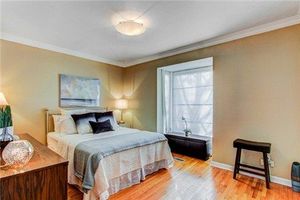 Bright bedroom with beige walls, hardwood floors, and elegant bedding in neutral tones.