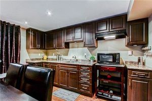 Elegant basement kitchen featuring dark wood cabinets and laminate flooring