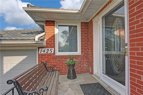 Modern red brick house exterior with white trim and landscaping features.
