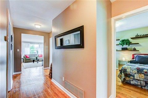 Hallway with neutral walls and hardwood floors showing multiple interior doorways.