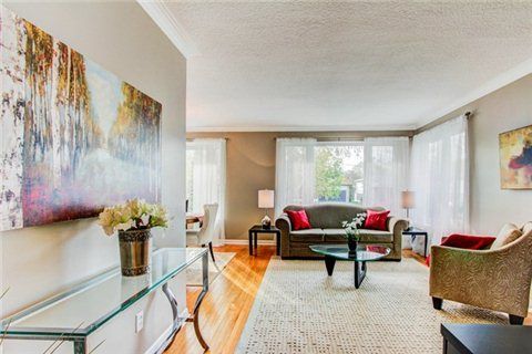 Elegant living space with glass console table, abstract wall art, and sofa.