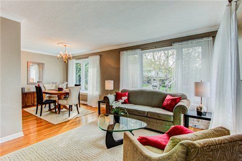 Spacious living room with dining area, sofa, and sheer white curtains covering large windows.