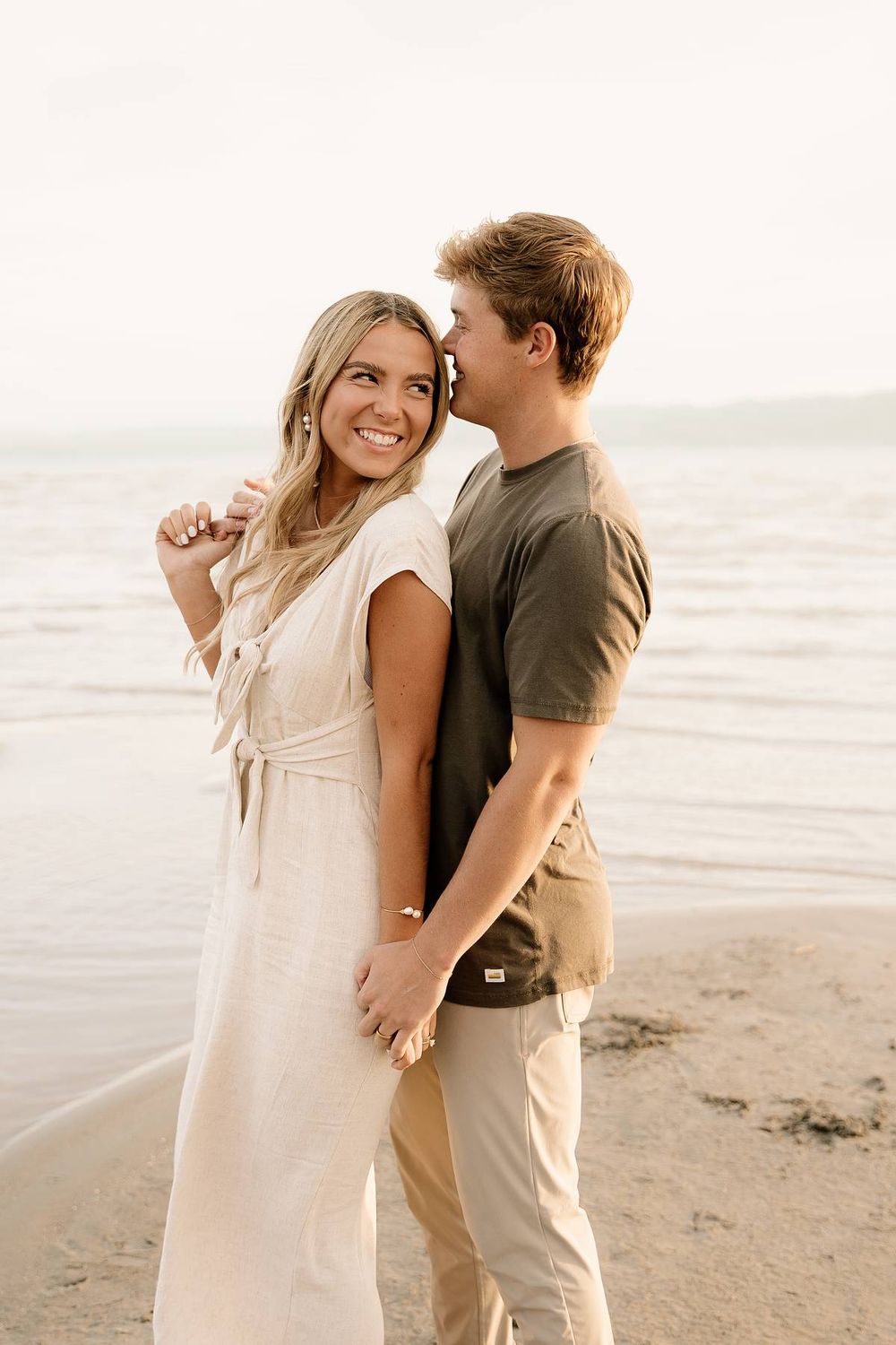 Joyful couple sharing a candid moment together on beach at sunset.