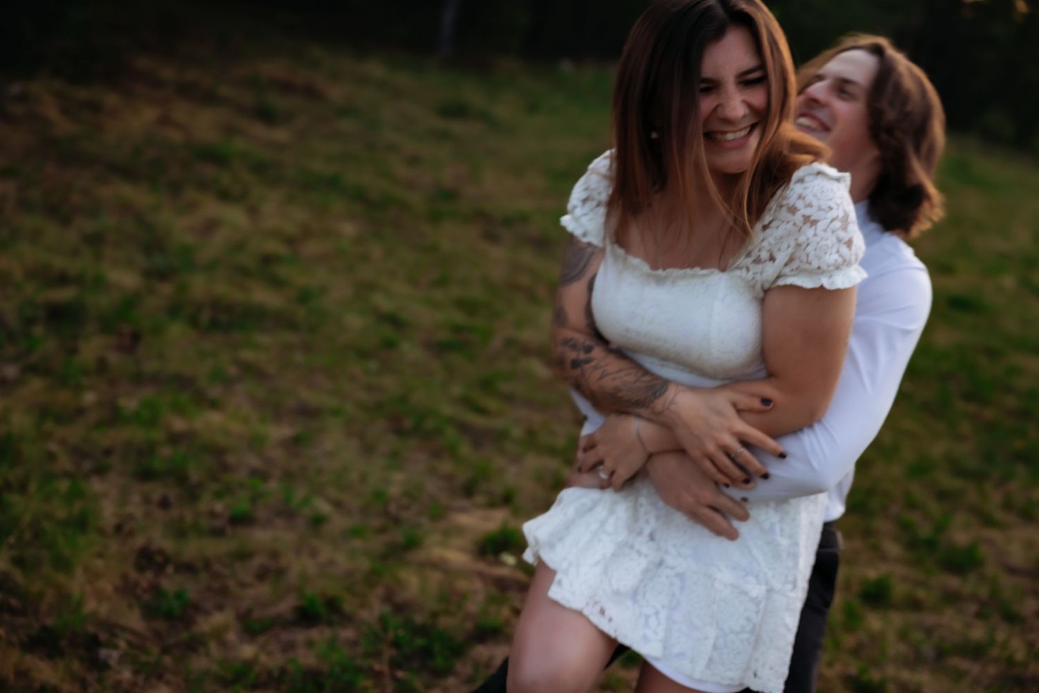 An intimate outdoor photoshoot of a couple sharing joyful moments together during sunset.