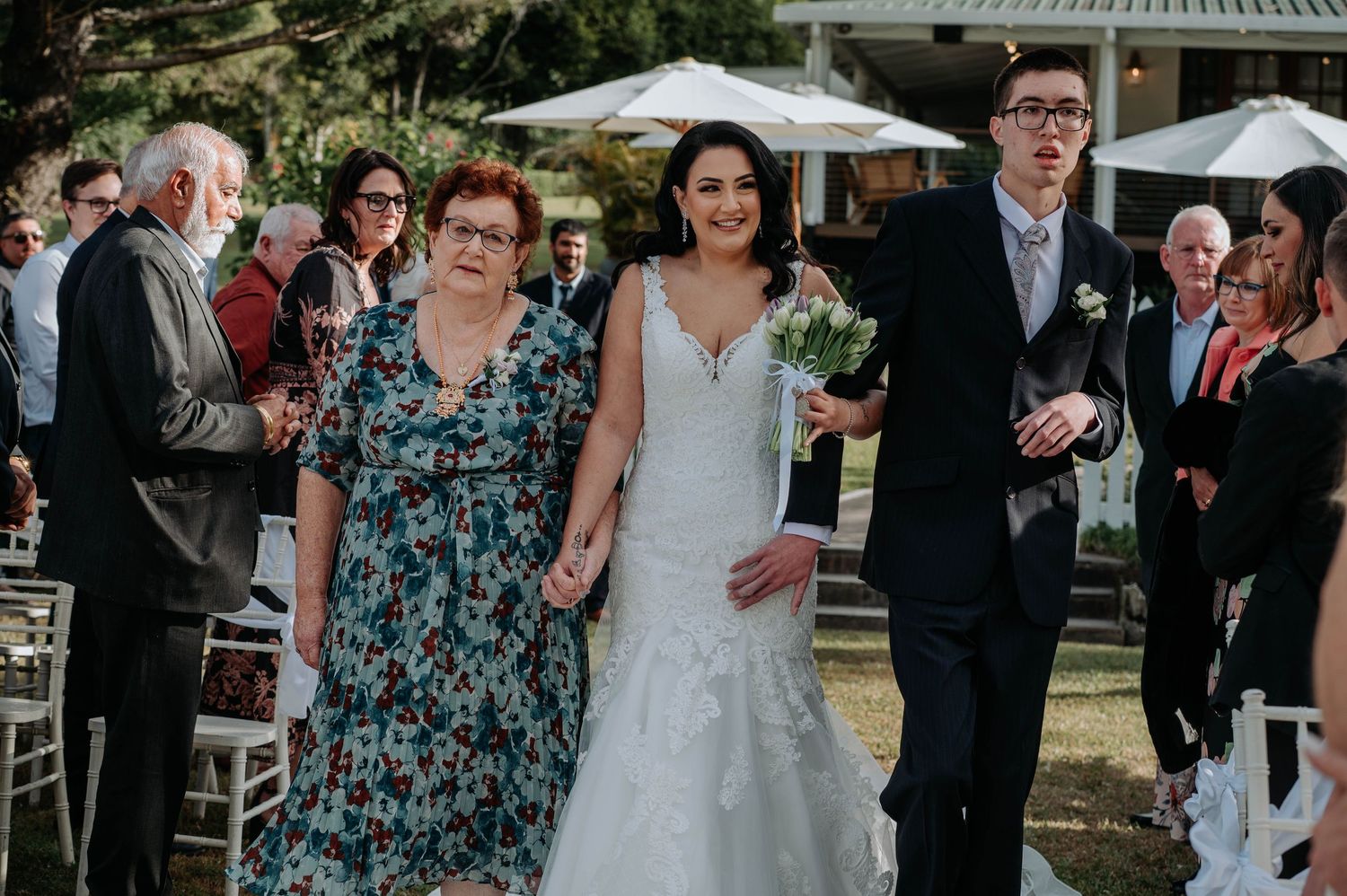 Wedding guests celebrate and dance together at an outdoor reception under white tent canopies.