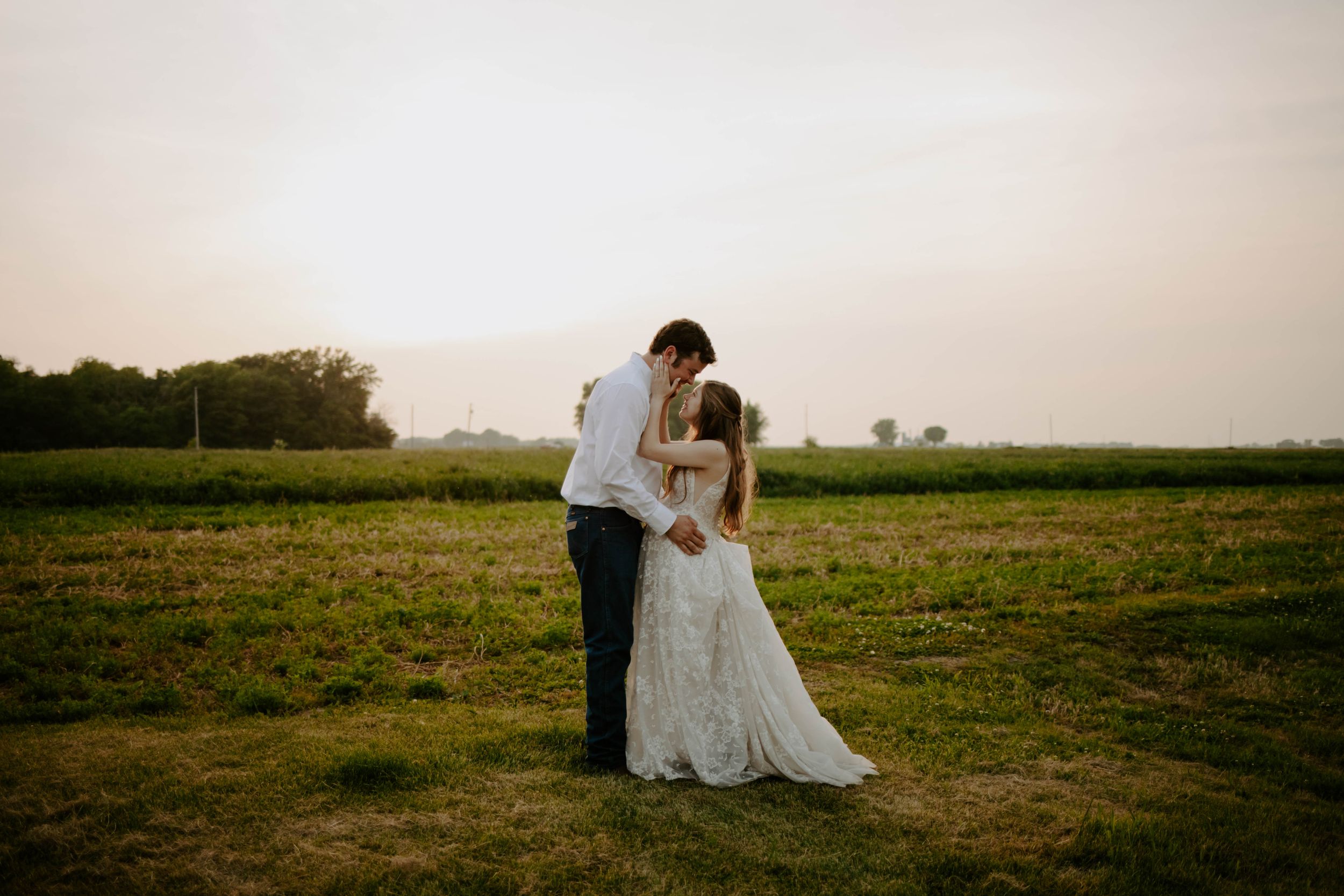 A romantic wedding photoshoot in a golden field at sunset with flowing white dress details.