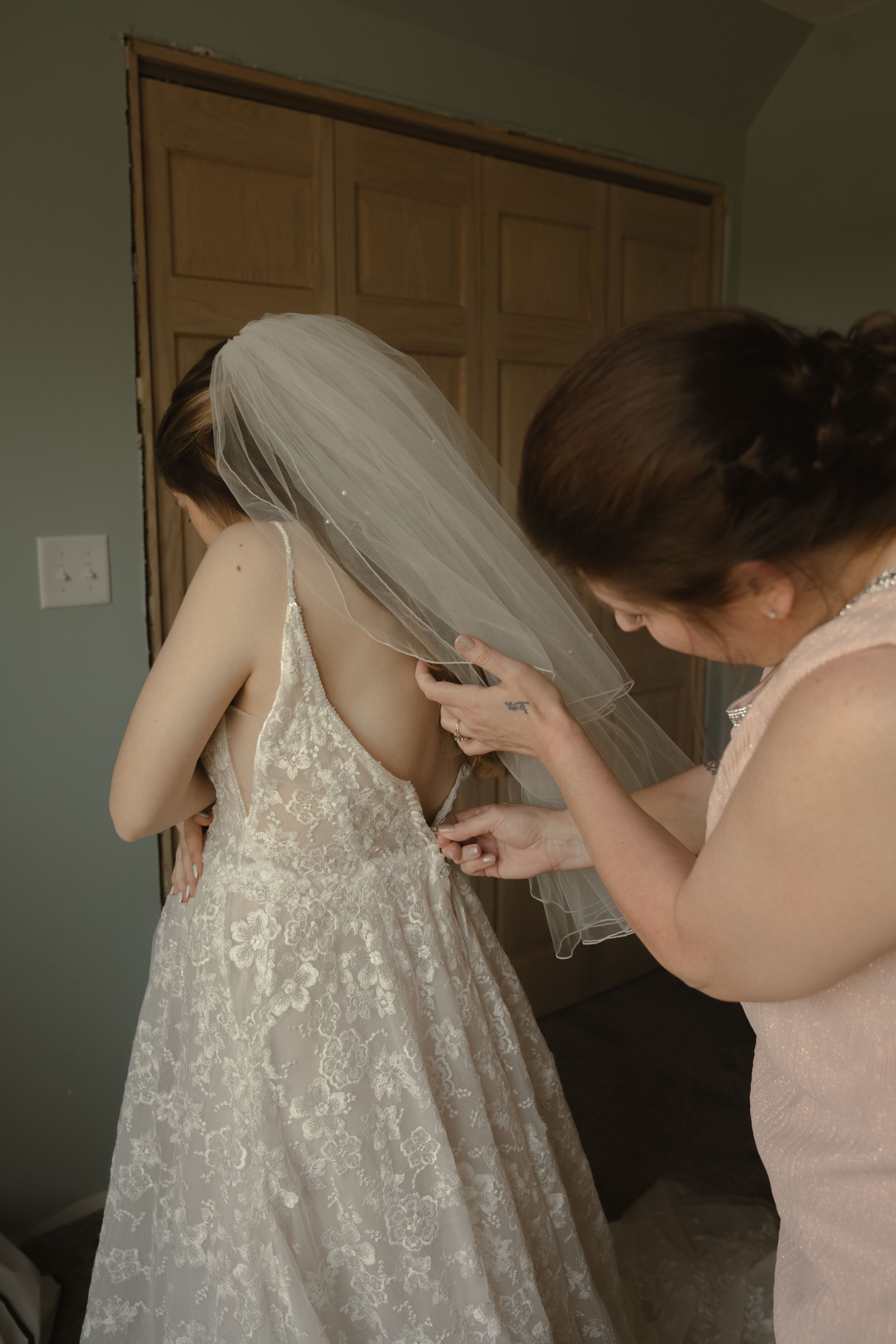 White lace wedding dress being adjusted and prepared before the ceremony.
