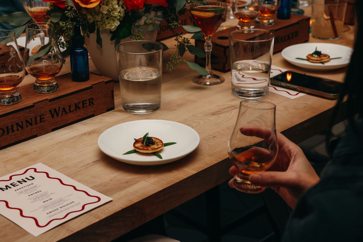 Wooden table setting at restaurant with plated food and menu cards.