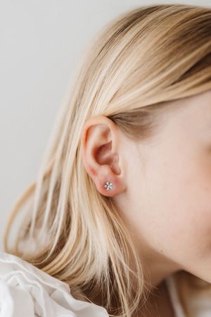 Profile view of delicate star earring against blonde hair with soft lighting.