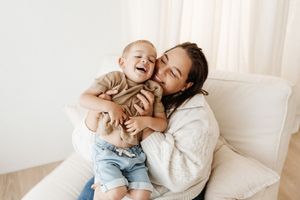 Intimate moment captured of playful interaction on white couch in natural lighting.