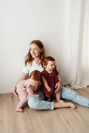 A casual indoor family portrait showing tender moments between children in pink and burgundy outfits.