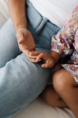 Close-up of hands touching tenderly on blue denim and floral fabric.
