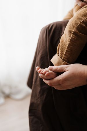 Close-up of hands cradling tiny baby feet in warm natural light.