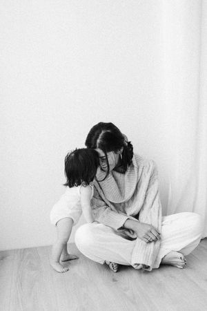 Black and white candid moment showing intimate interaction on wooden floor.
