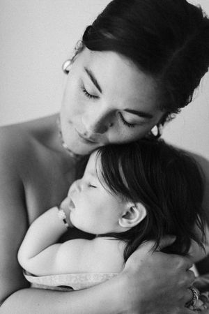 Tender black and white portrait of nurturing moment with sleeping infant.