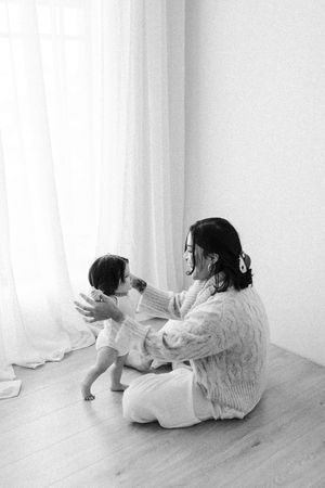 Black and white photo showing tender interaction in minimalist white room setting.