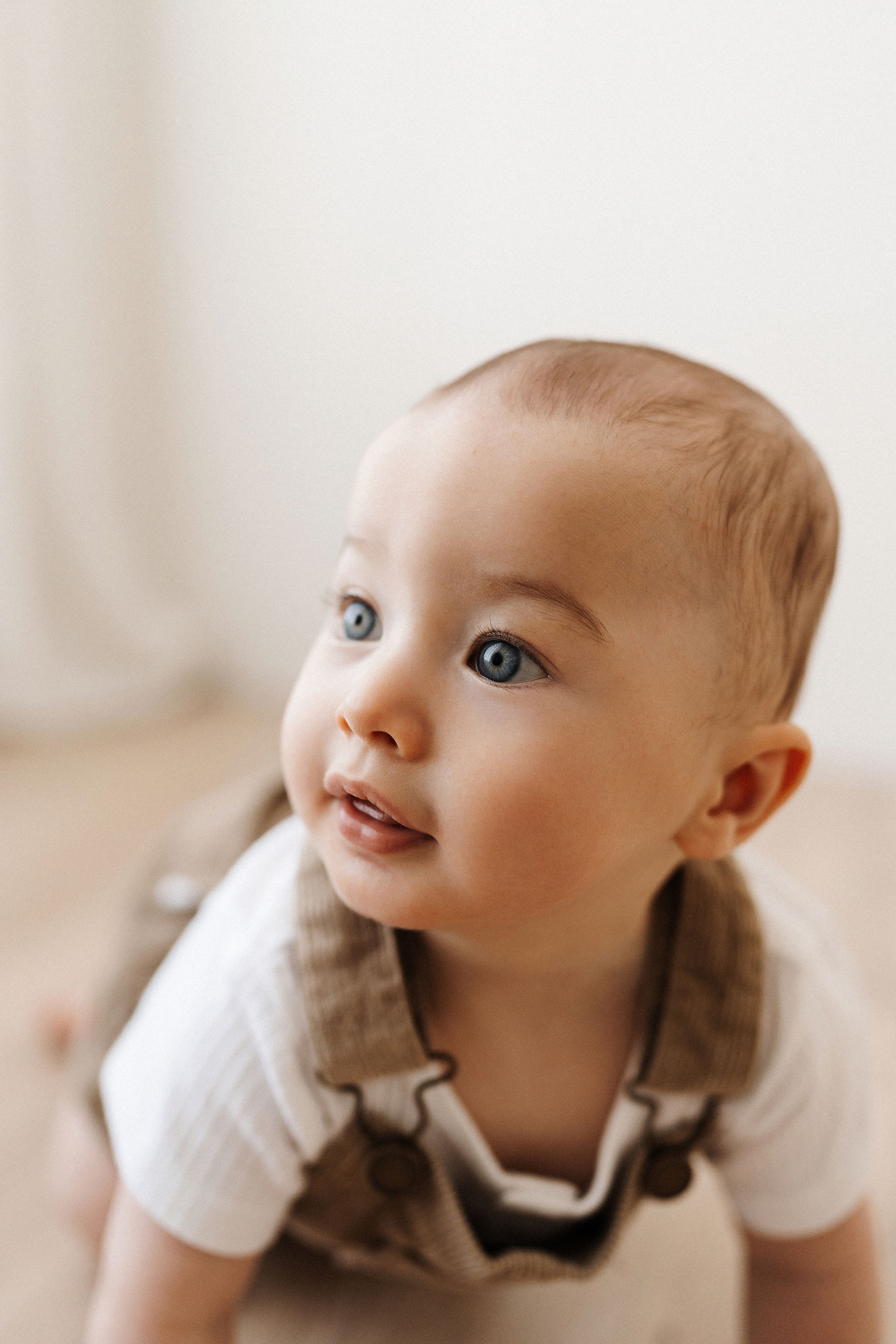 Close up series of baby expressions while lying down in white clothes.