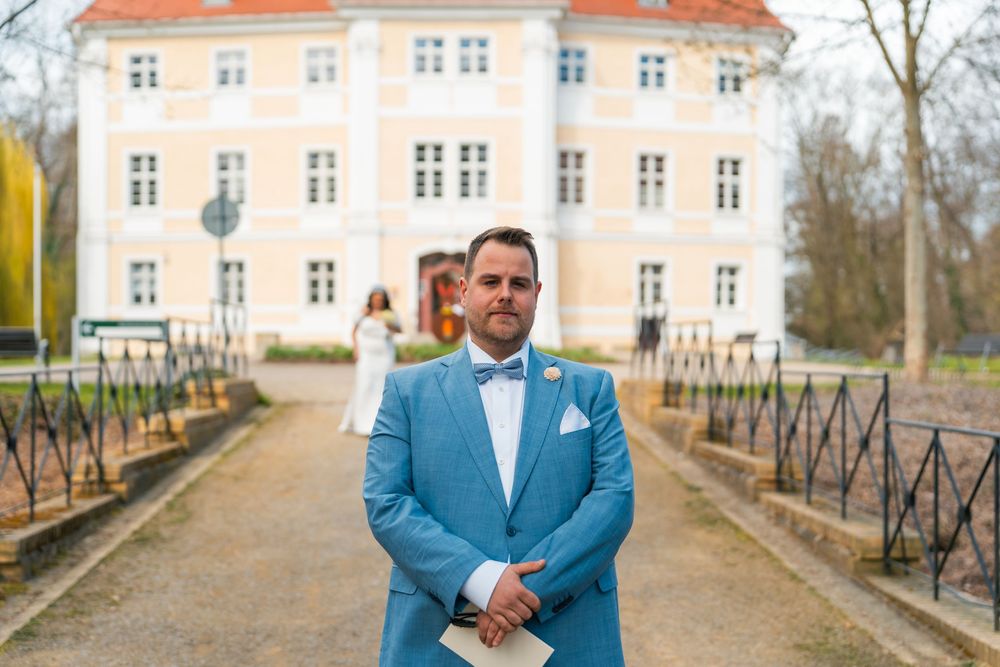Bräutigam in blauem Anzug wartet vor Schloss Vetschau