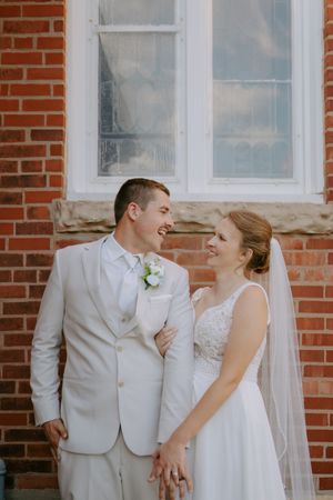 A joyful wedding moment captured against a brick wall backdrop.