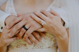 Close-up detail of hands with wedding rings and jewelry.