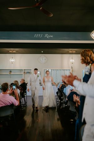 Wedding guests dance and celebrate in a dimly lit reception venue.