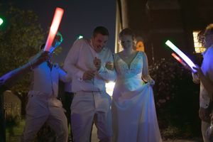 Wedding party members hold colorful light sabers while posing in the dark.